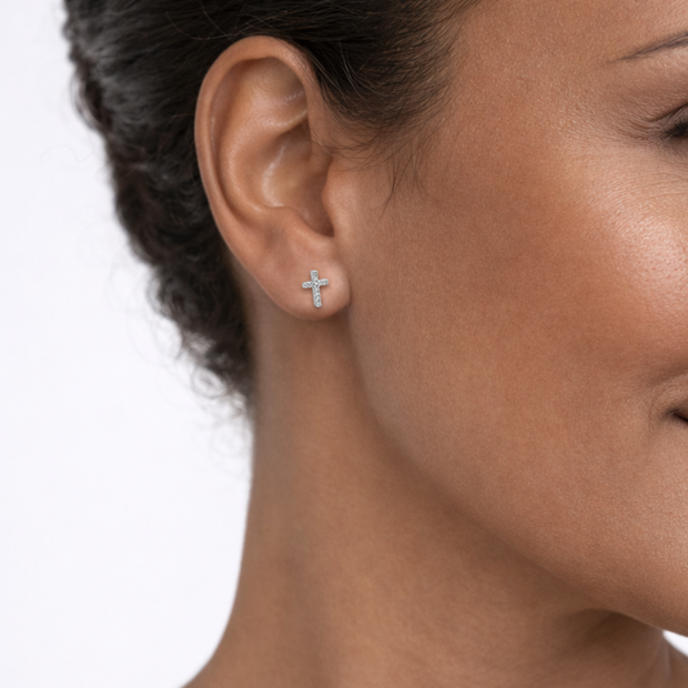 Close-up of a woman wearing a cross-shaped earring on a white background