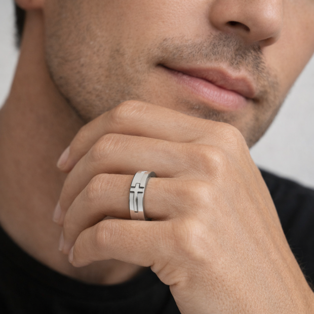 Close-up of a man's hand wearing a silver ring with a cross design.