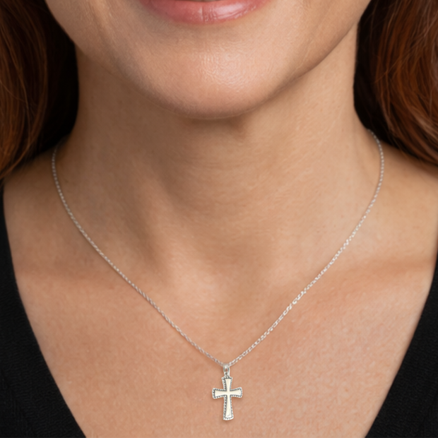 Silver cross necklace on a person's neck